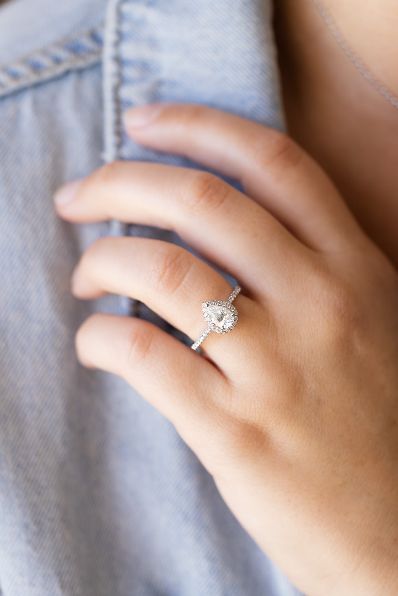 Pear Shape Diamond Halo Ring on lady's hand wearing denim jacket