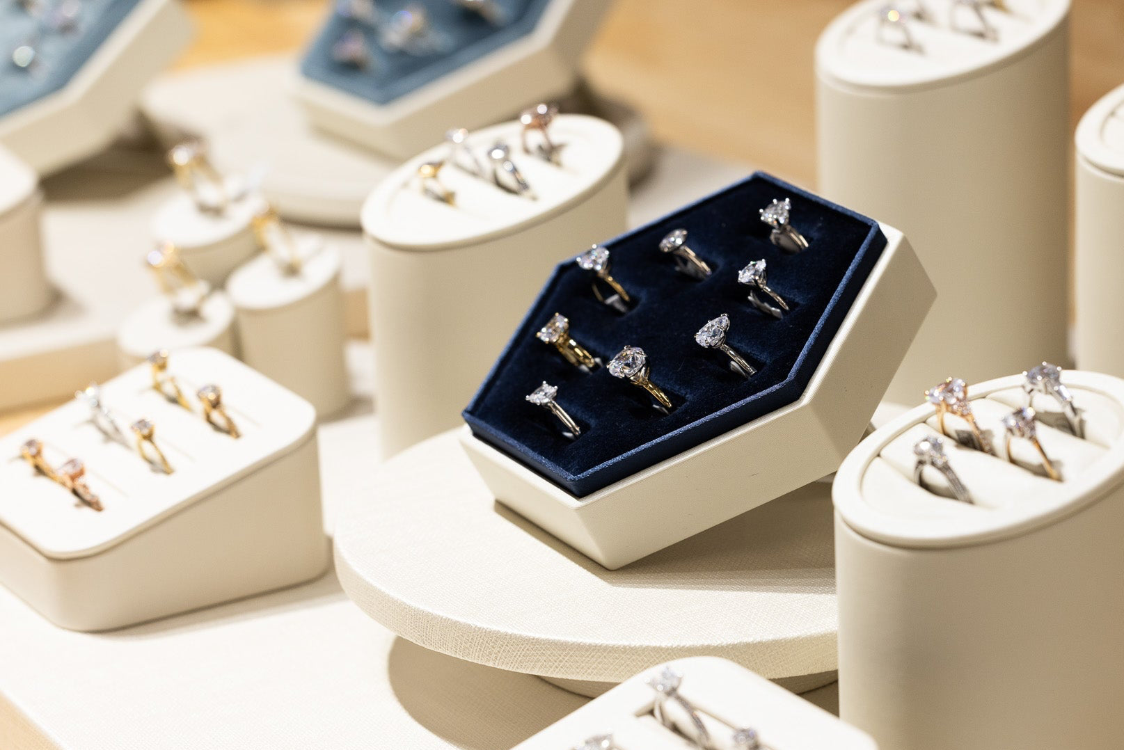 Jewelry display with rings on white cylindrical stands and a blue box.