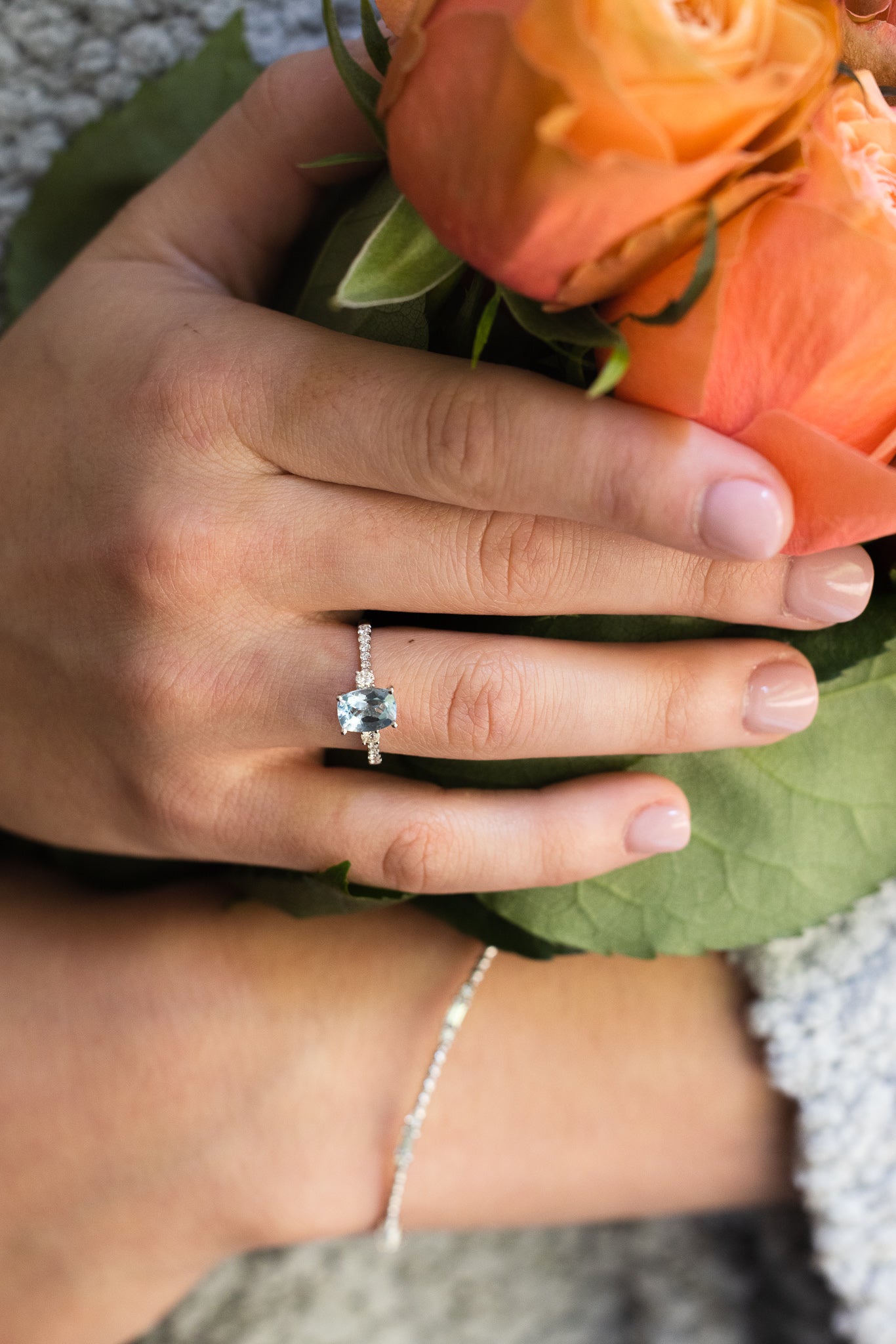 Aquamarine & Diamond Ring on lady's hand holding roses