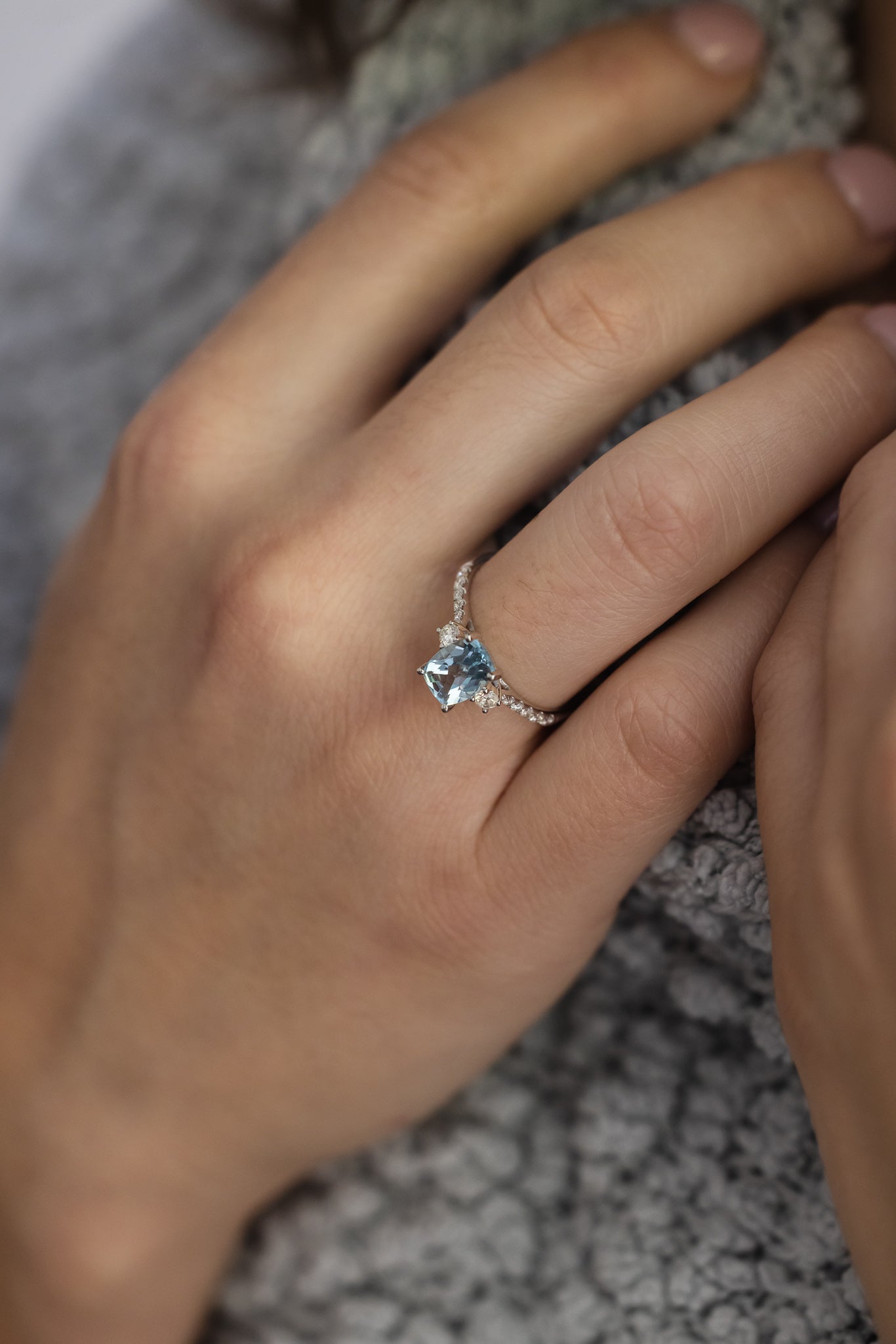 Aquamarine & Diamond Ring on lady's hand wearing grey sweater 