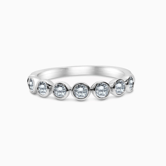 A 14k white gold bezel set diamond band with 7 round-cut diamonds.