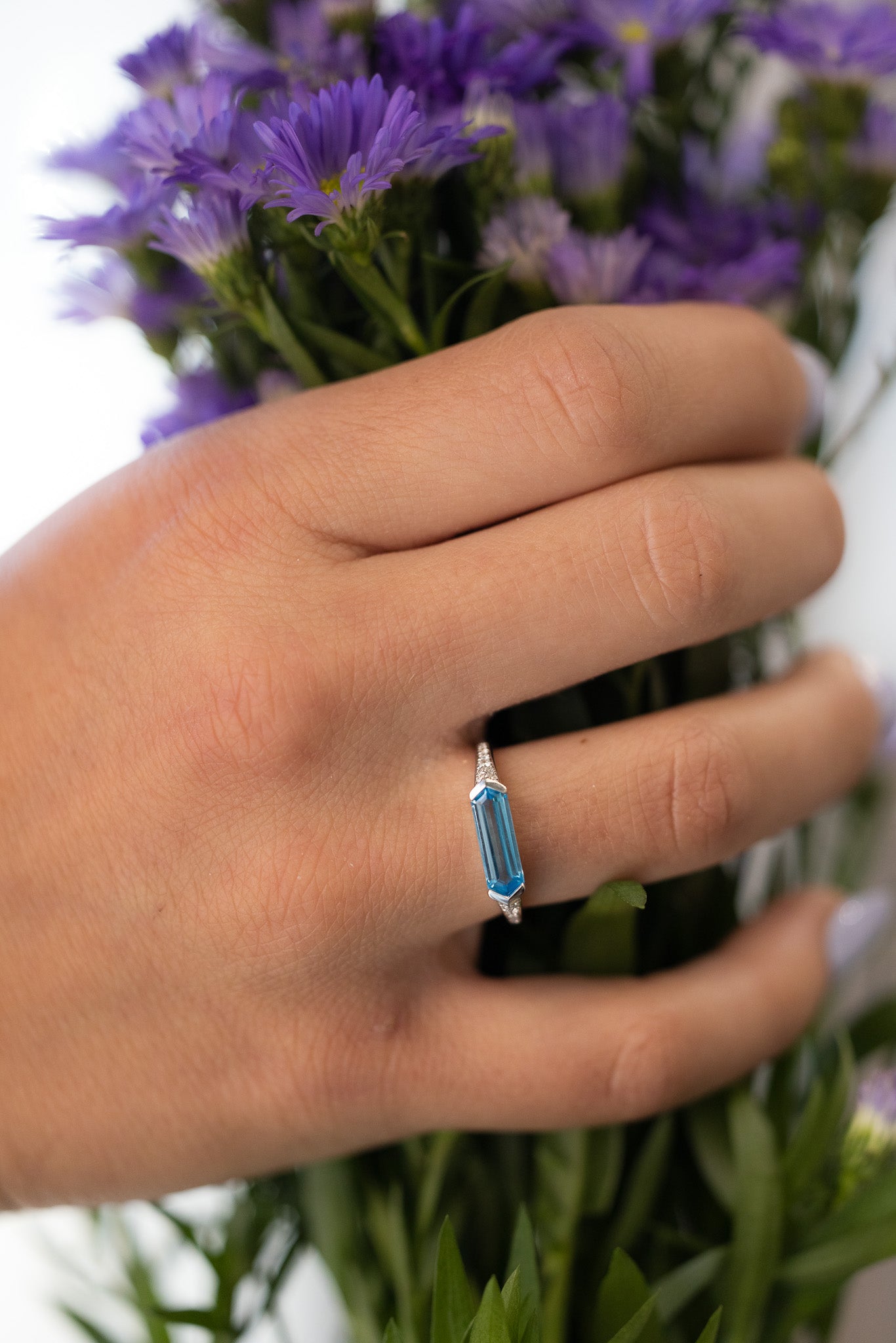 East West Blue Topaz Ring on hand holding flowers