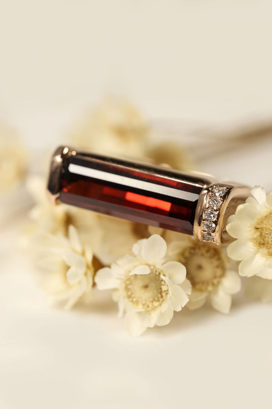 Rose Gold Hand Carved Ring with Garnet and Diamonds on flower display
