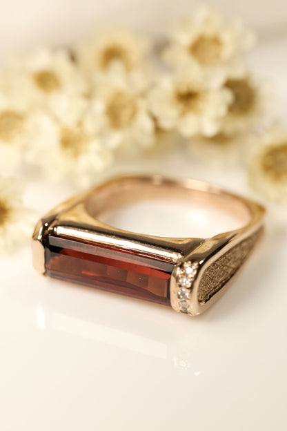Rose Gold Hand Carved Ring with Garnet and Diamond Accents with floral background