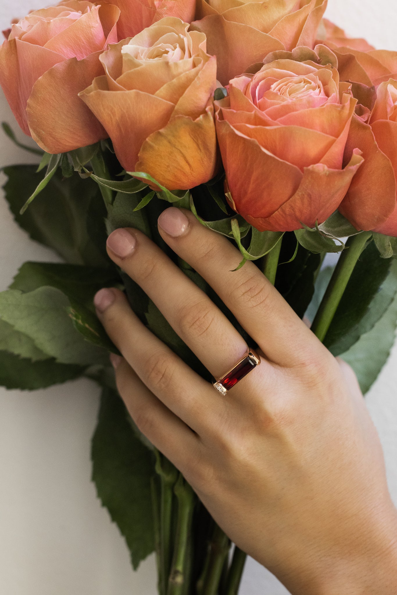 Rose Gold Hand Carved Ring with Garnet and Diamond Accents on hand holding roses